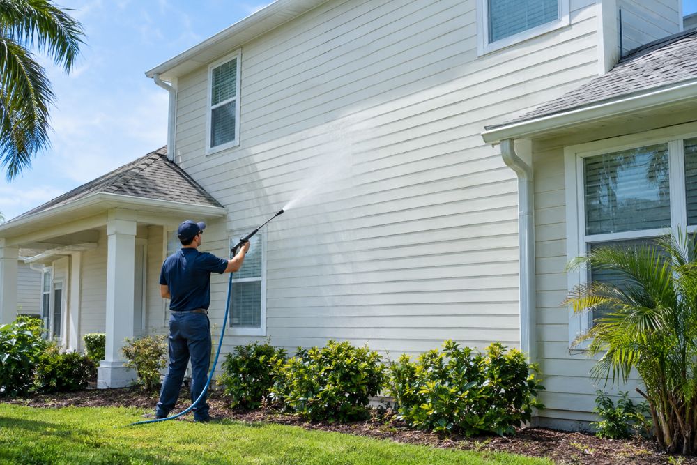 Technician soft washing the siding of a two-story home